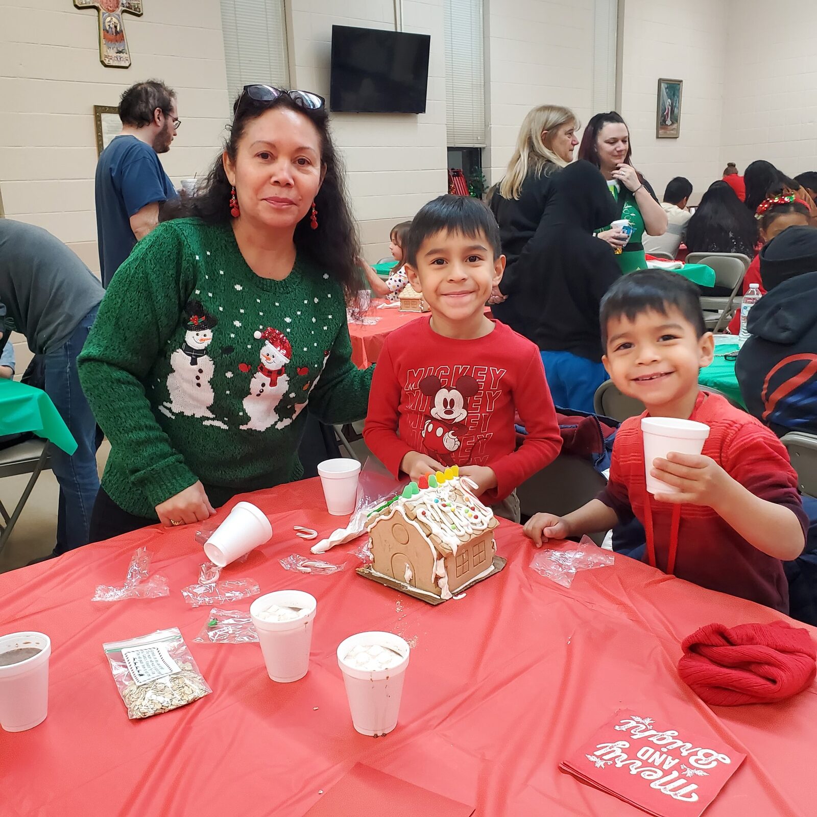 Families decorating gingerbread houses together at a school event